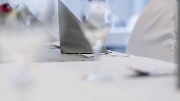 Una mesa con un objeto triangular, posiblemente un porta servilletas, en una habitación con techo y paredes blancos.