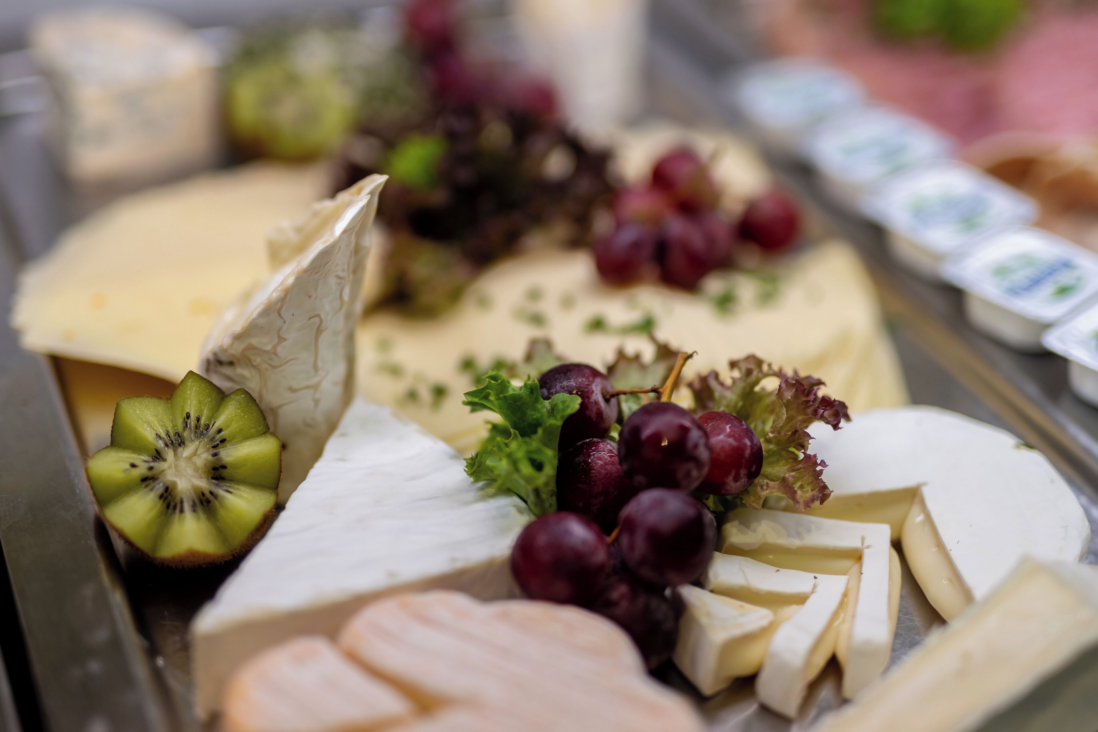 A variety of cheeses and fruits on a platter.