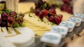 Una tabla de quesos con diversos quesos, uvas y hierbas.