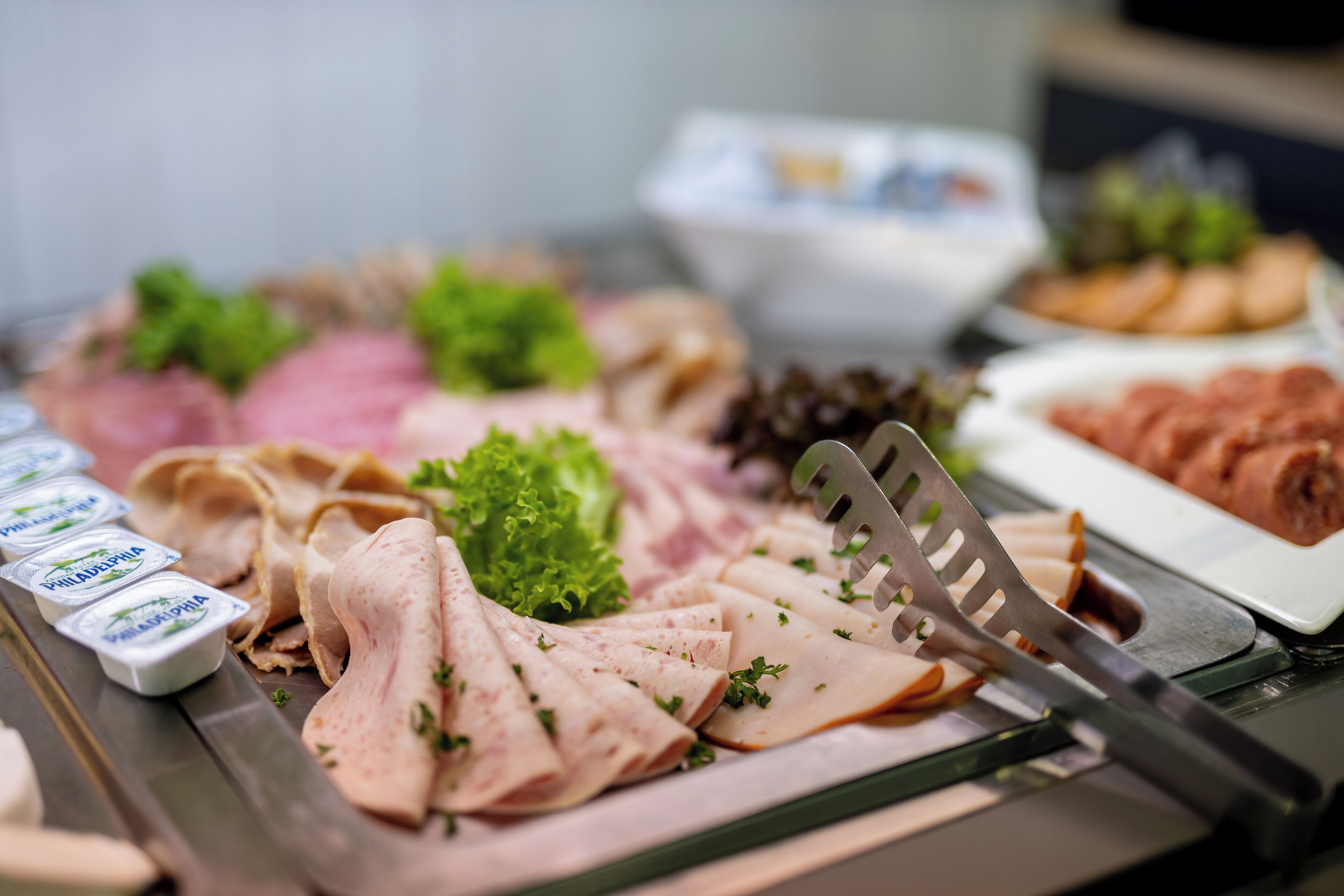 A buffet with various meats, vegetables, and dips.