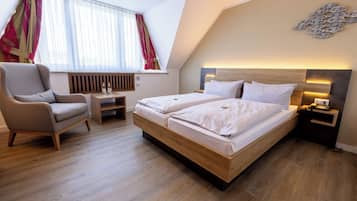 Ein modernes Hotelzimmer mit einem großen Bett, einem Sessel, einem kleinen Tisch und einer Heizung.