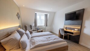 Une chambre d’hôtel moderne équipée d’un grand lit, d’un bureau, d’une chaise, d’une télévision et d’une fenêtre avec des rideaux.