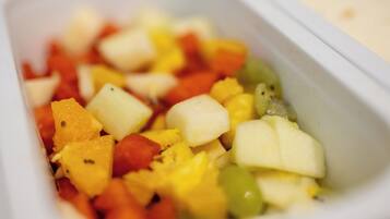 Primer plano de un recipiente con frutas y verduras cortadas en cubos.