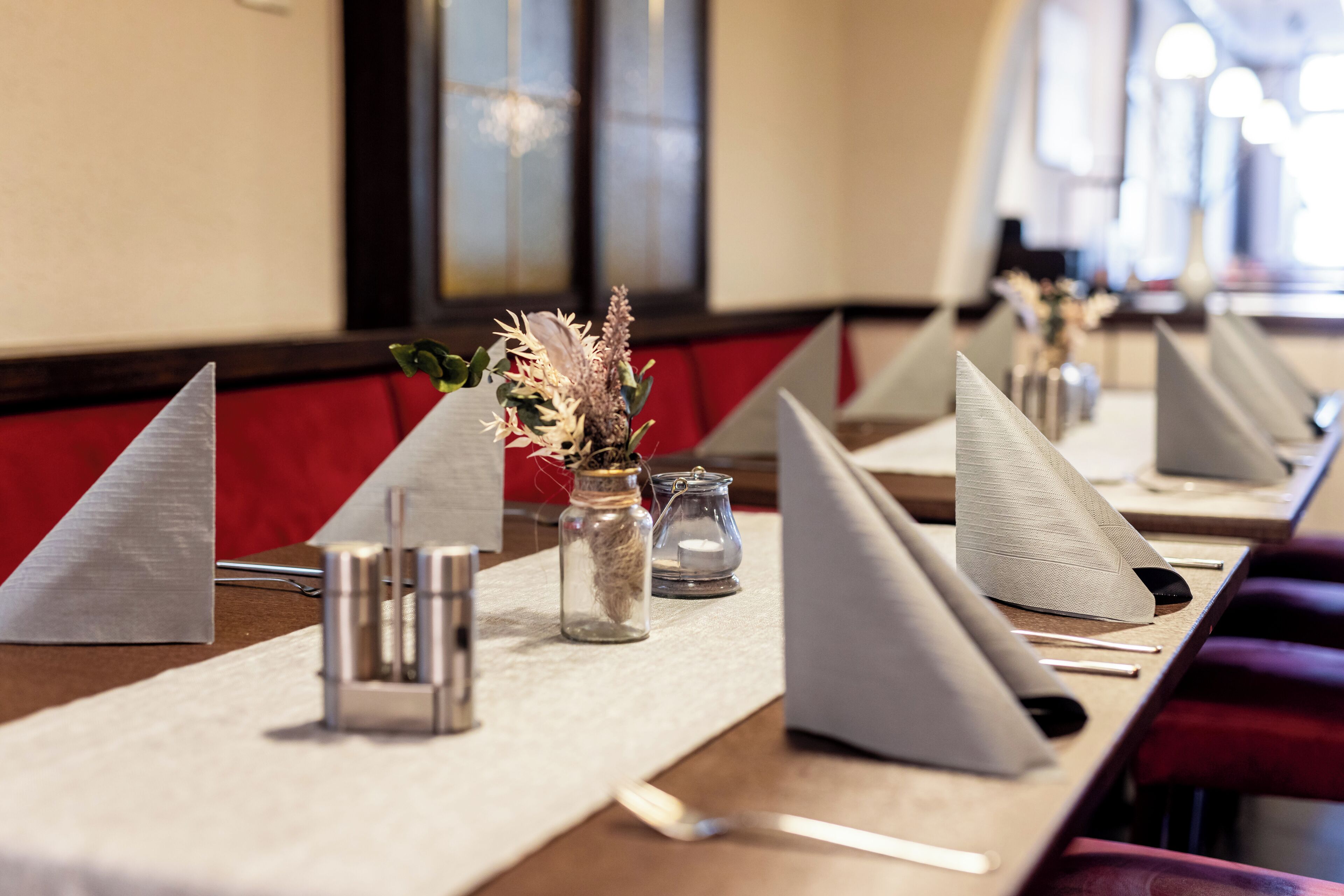 A conference room with tables set for meetings, each with a notepad, pen, and a small vase with dried flowers.