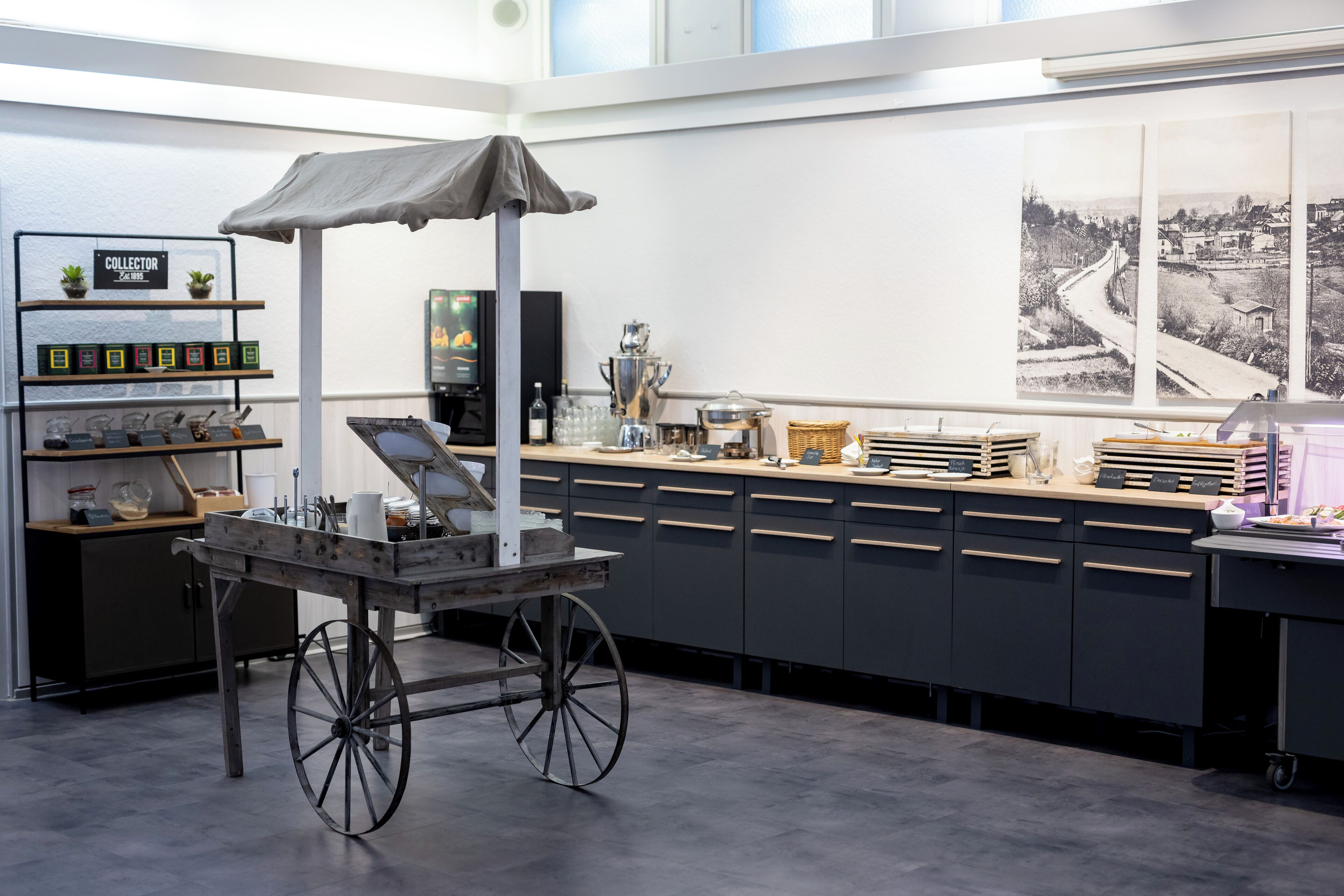Een moderne keuken met een karretje, planken met potten, een koffieapparaat en een groot raam met uitzicht.