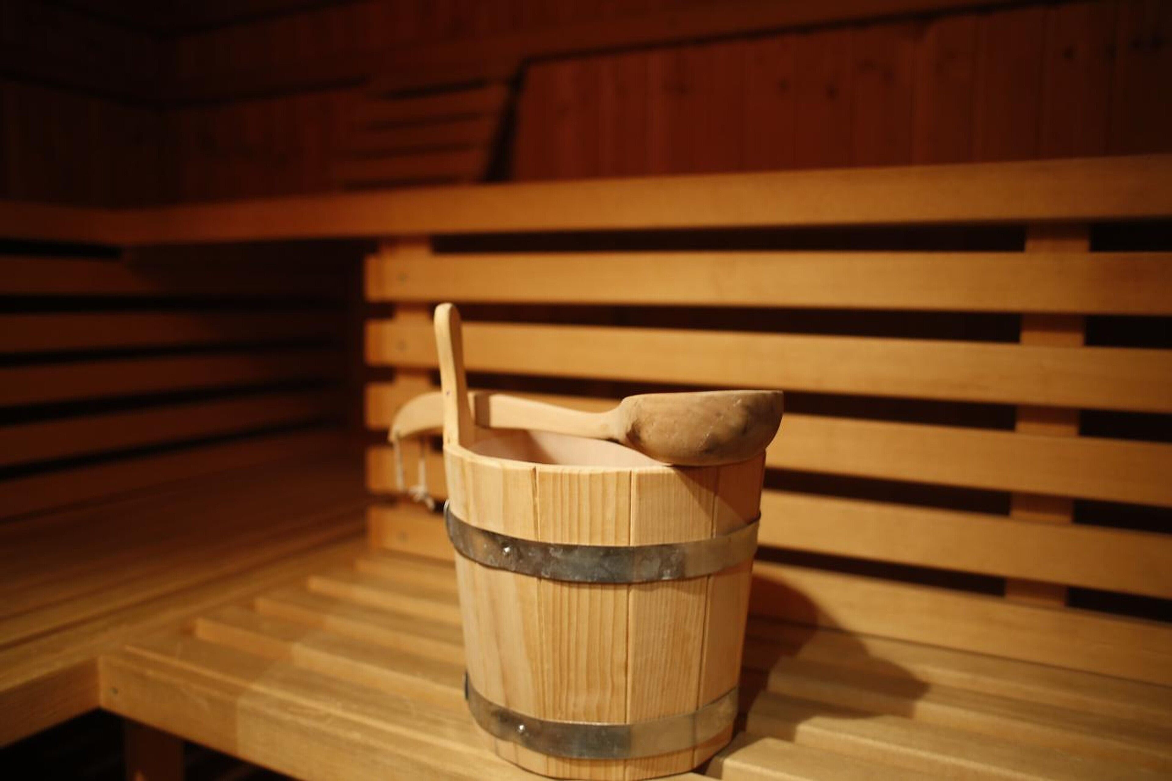 A wooden bench with a wooden bucket containing a wooden mallet.