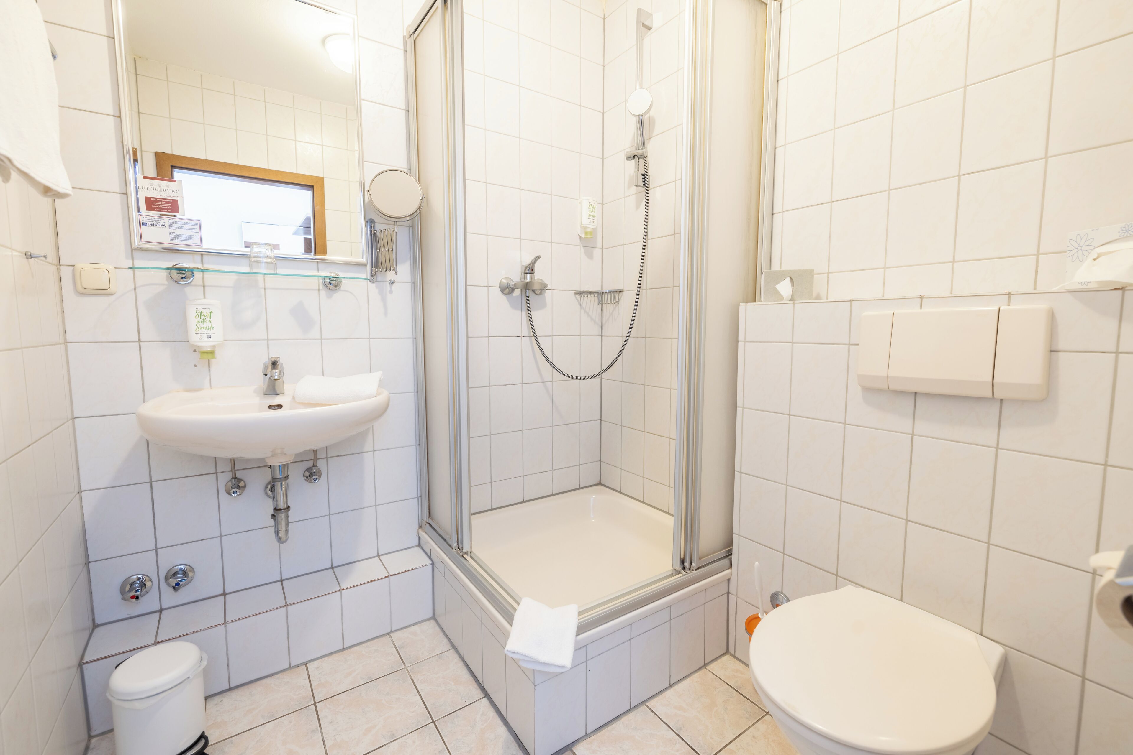 A bathroom with a shower, sink, toilet, and a mirror.
