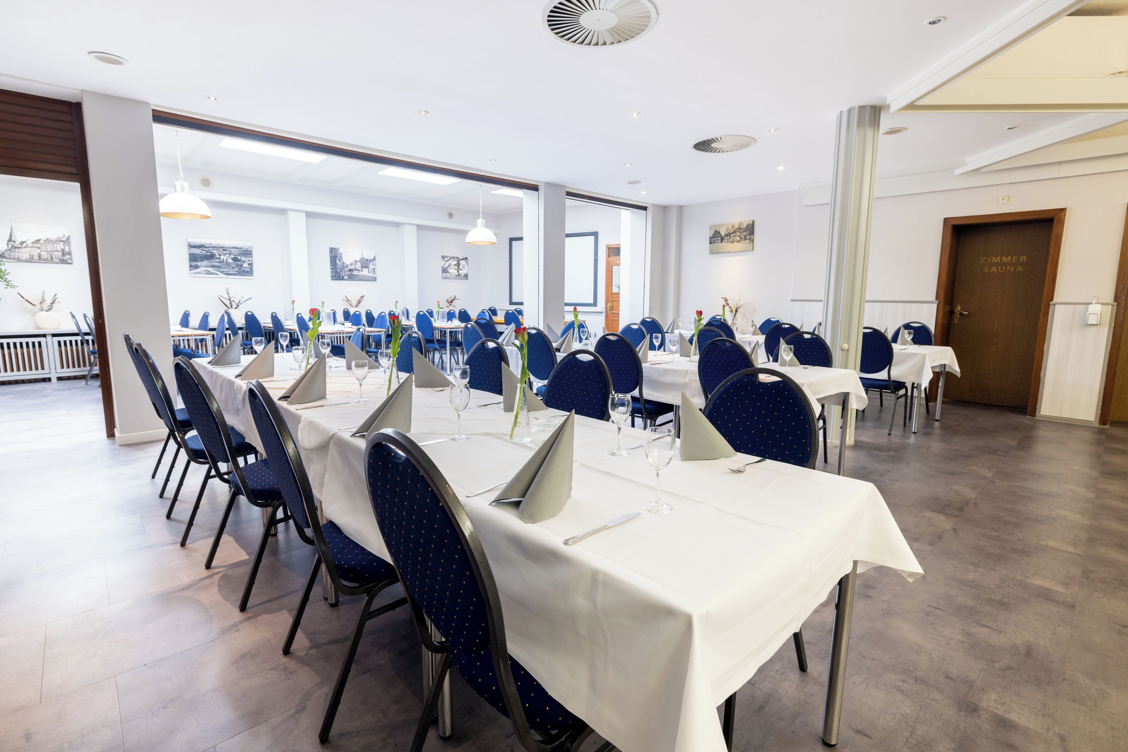 Un'ampia sala da pranzo con diversi tavoli e sedie, ampie finestre e un arredamento moderno.