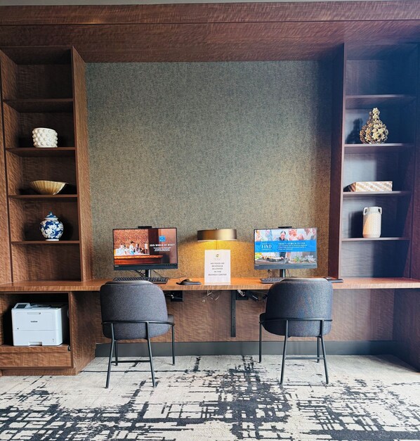 A hotel reception desk with two monitors, a printer, and a computer.