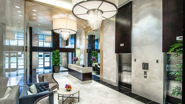 Eine großzügige Lobby mit einer Rezeption, einer Sitzecke und einer modernen Chandelier.