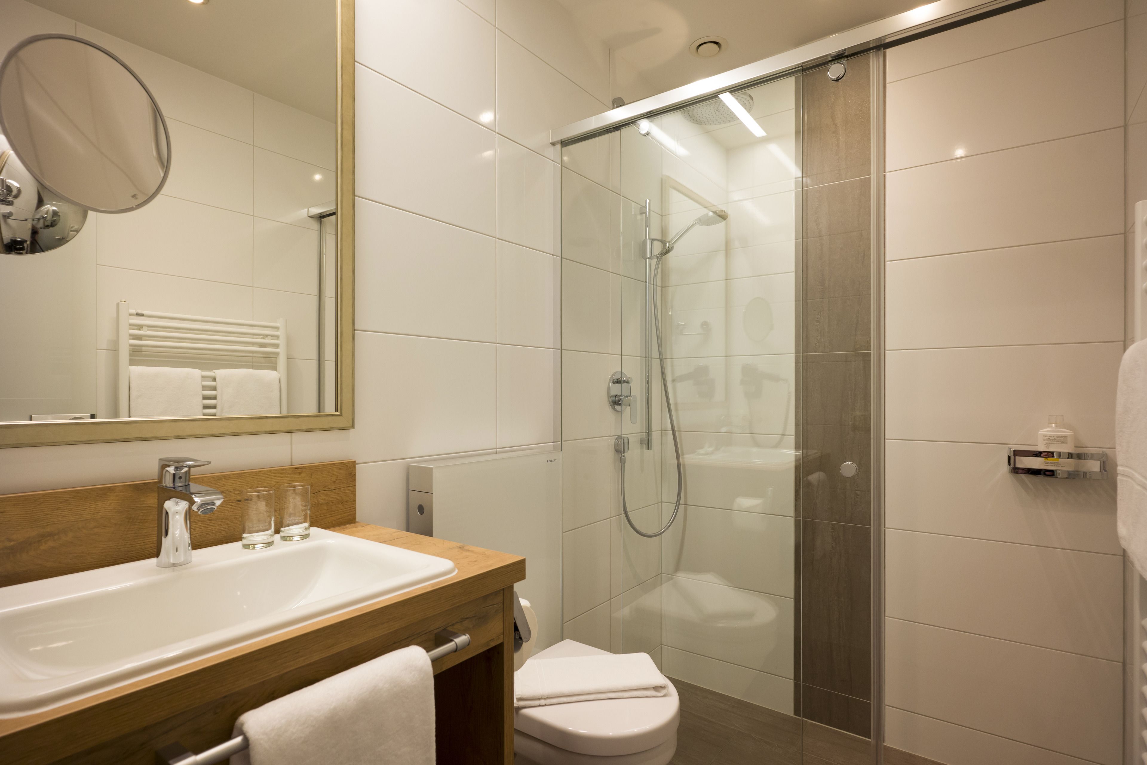 A modern bathroom with a glass-enclosed shower, a wooden vanity with a sink, and a mirror above the vanity.