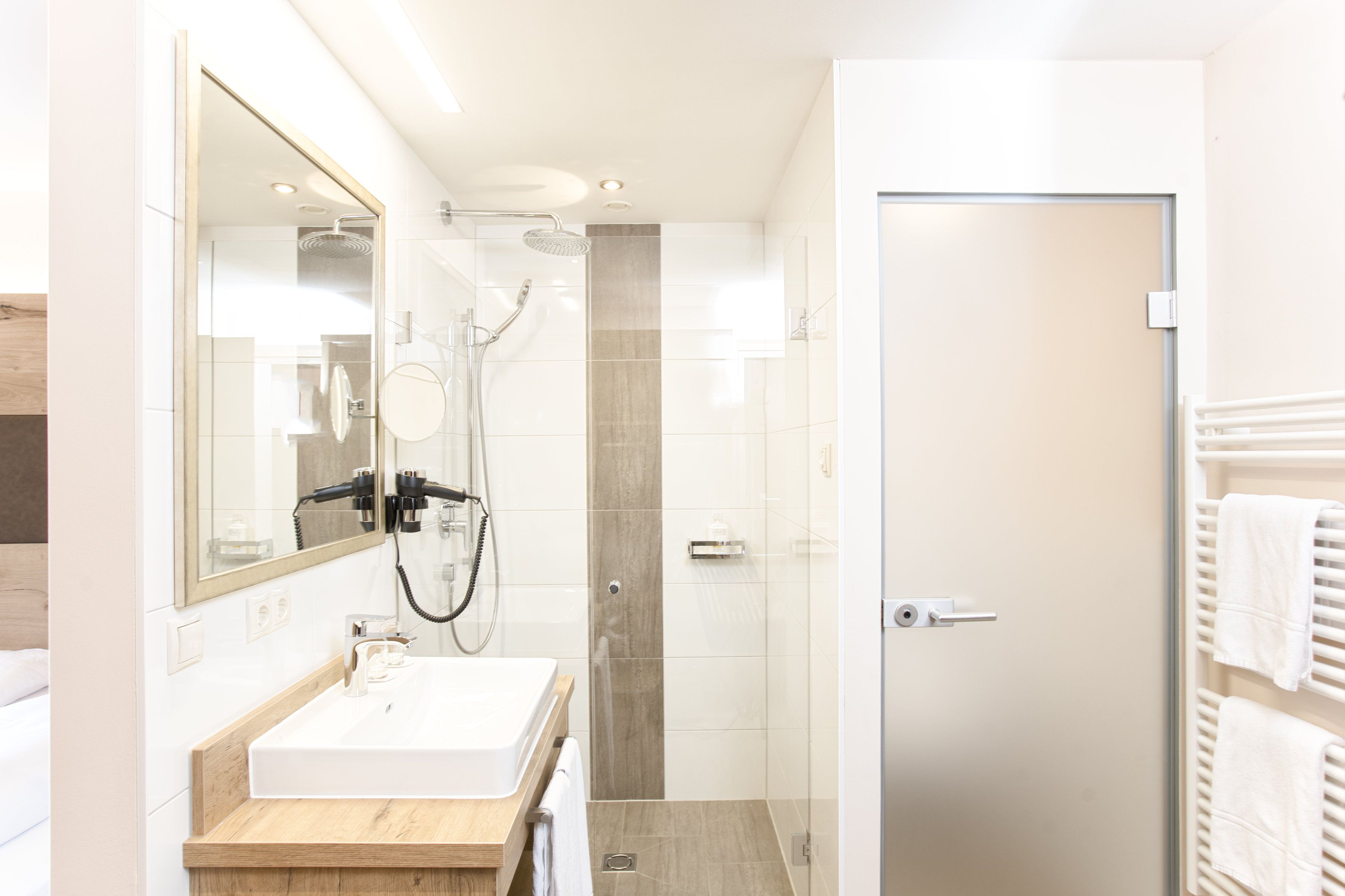 Un baño moderno con un espejo grande, un lavabo y una zona de ducha.