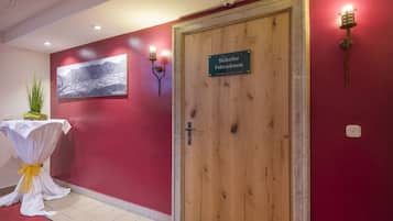 Una porta in legno con la scritta "Skikeller Fahrraum", un cartello, una fotografia incorniciata a parete e un tavolo ricoperto da una tovaglia bianca e decorato con un nastro giallo.