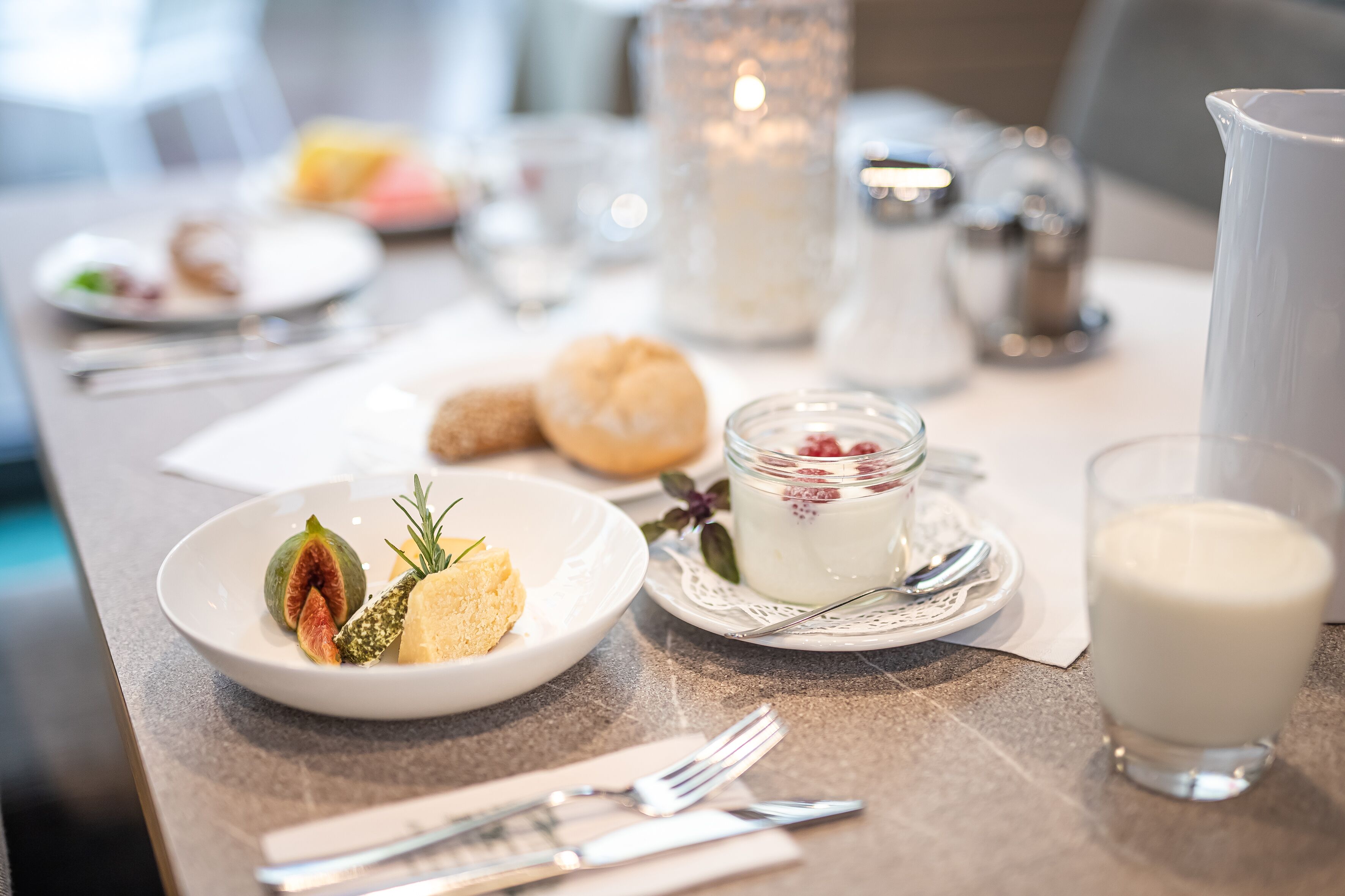 A breakfast setting with a plate of food, a glass of milk, and a candle on the table.