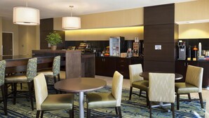 Un hall d'hôtel avec un comptoir d'accueil, un espace salon et une cuisine en arrière-plan.