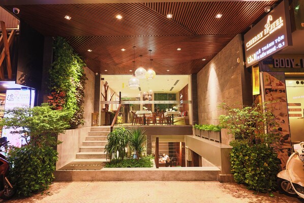 A hotel entrance with a wooden ceiling, indoor plants, and a staircase leading to the upper floor. - Cherry Boutique Hotel (Ho Chi Minh City)