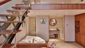 A modern bathroom with a freestanding bathtub, a wooden staircase, and a round mirror. - Cherry Boutique Hotel (Ho Chi Minh City)
