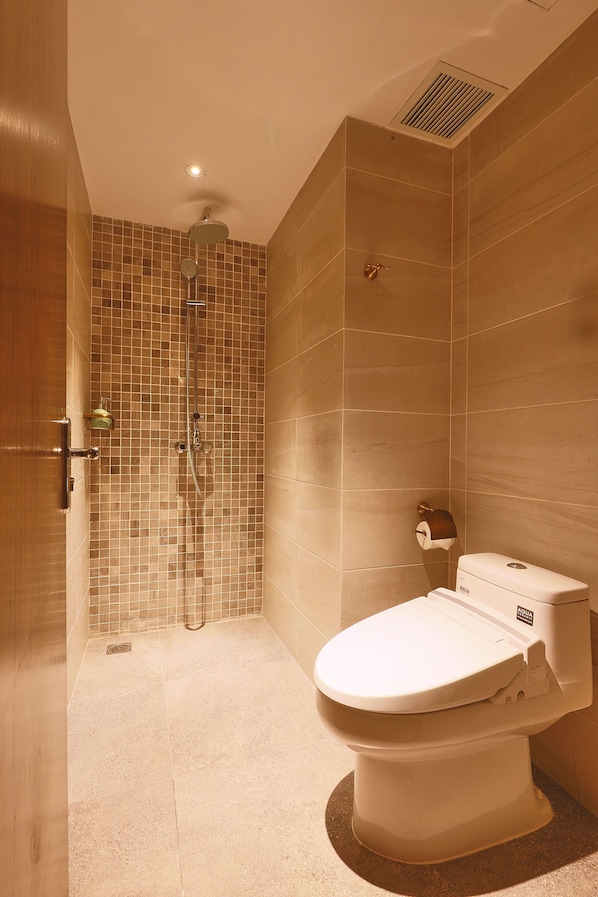 Un baño con ducha, inodoro y pared de azulejos.