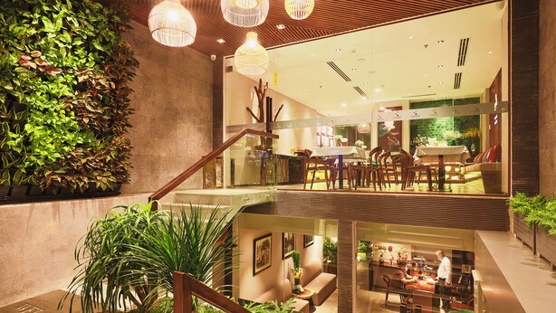 A modern hotel lobby with a staircase, indoor plants, and a dining area. - Cherry Boutique Hotel (Ho Chi Minh City)