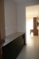 Una cocina moderna con armarios oscuros, una encimera y vista a un comedor con una silla y una mesa.