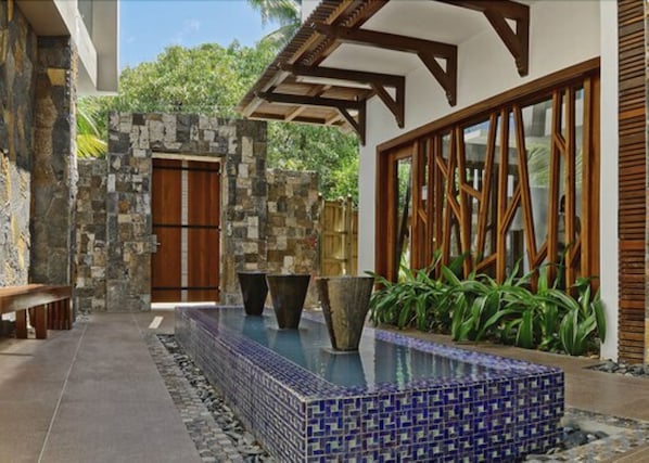 A pool area with stone walls, a wooden door, and large planters.
