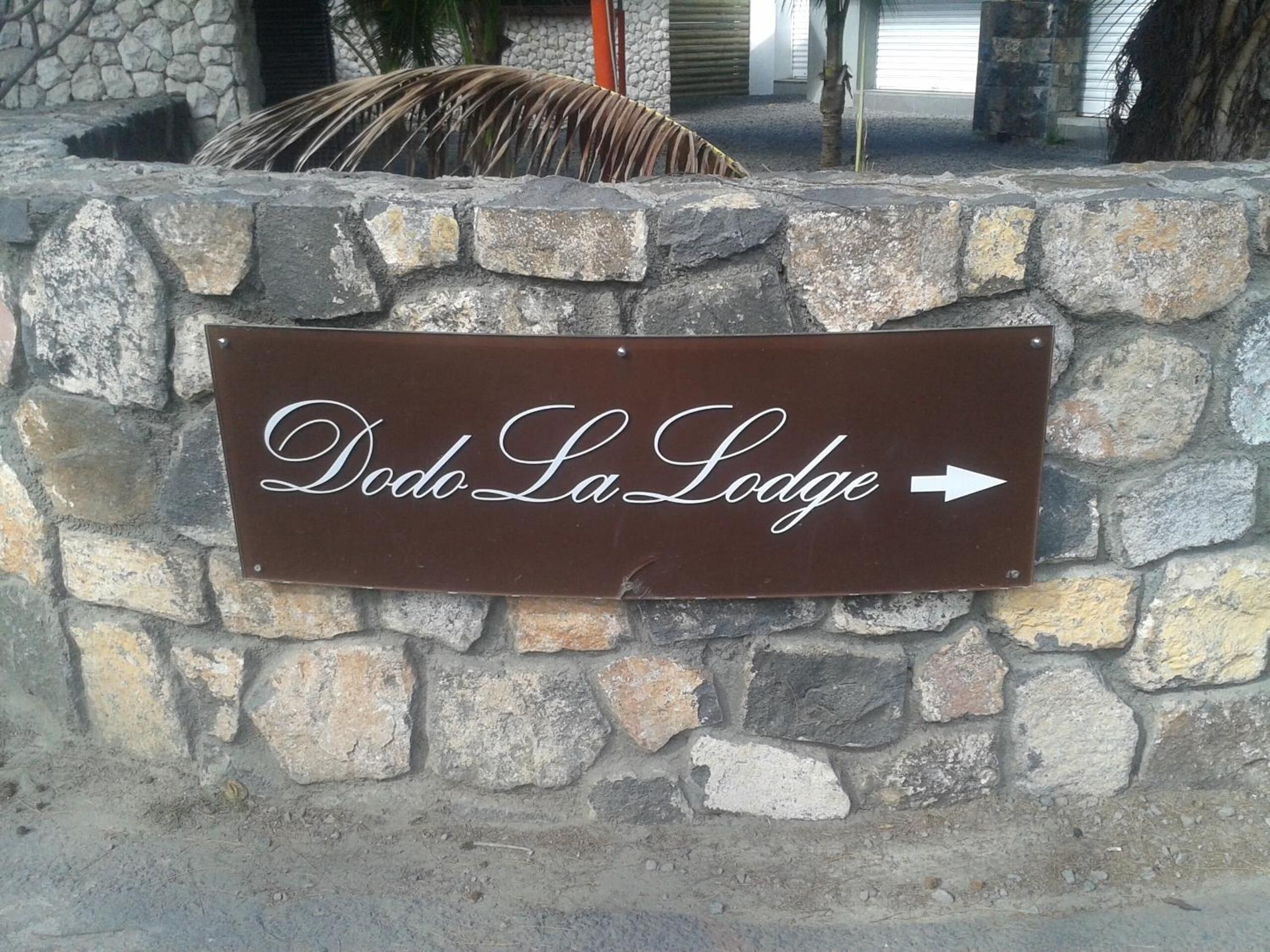 Eine Steinmauer mit einem Schild, das in Richtung rechts auf Dodo La Lodge verweist.