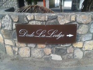 A stone wall with a sign for Dodo La Lodge pointing to the right. - Dodola Lodge (Grand-Baie)