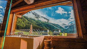 Una cabaña de madera con un ventanal grande con vistas a un paisaje montañoso.