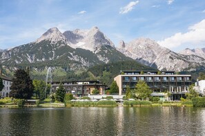 A hotel with a view of mountains, a lake, and outdoor seating. - Ritzenhof – Hotel und Spa am See (Saalfelden am Steinernen Meer)