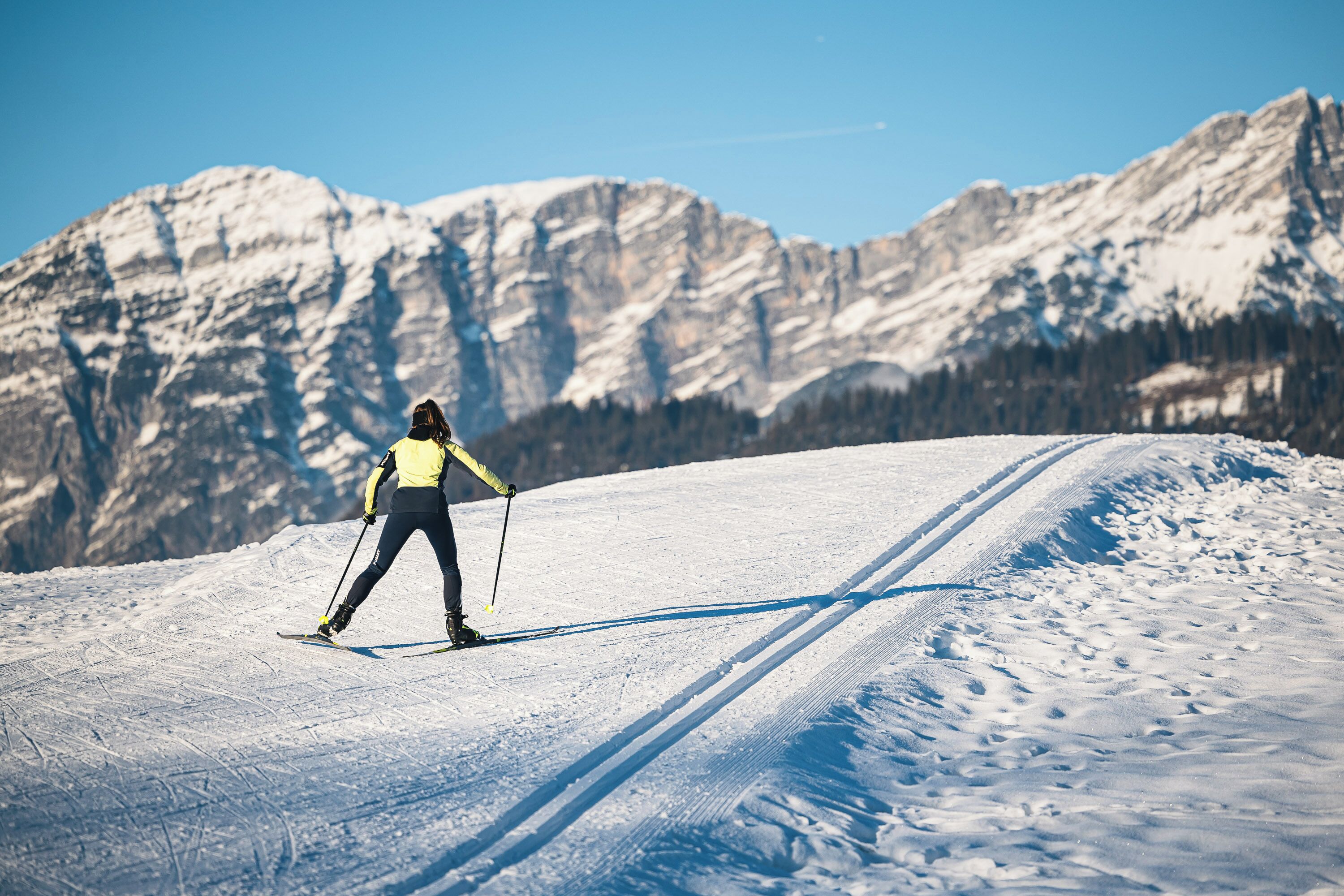 A person skiing on a snow-covered slope with mountains in the background.