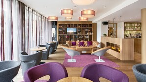 A modern lounge area with leather sofas, round tables, and a bar area with a fireplace.