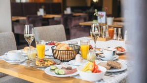 A breakfast setting with various dishes, drinks, and a basket of bread.