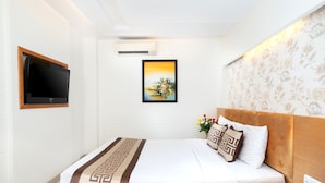 Habitación de hotel con una cama, televisión, un cuadro en la pared y un estampado floral en el papel tapiz.