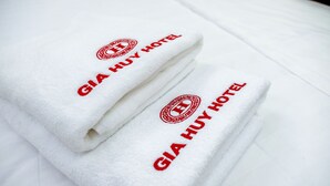 Una pila de toallas blancas con la leyenda 'GIA HUY HOTEL' impresa en rojo.