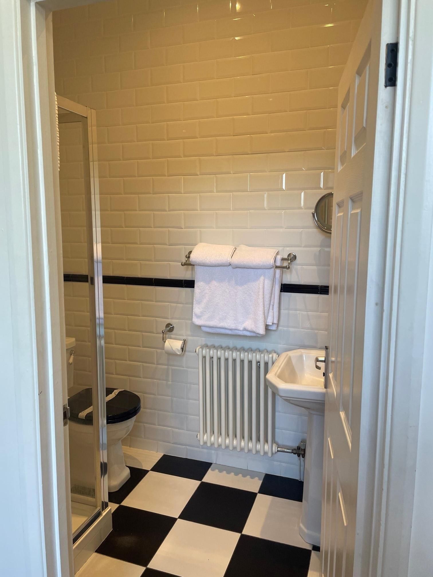A bathroom with a black and white checkered floor, a white toilet, a white sink, and a towel rack with two towels.