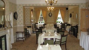A formal dining room with multiple tables set for service, a chandelier, and a fireplace. - Canterbury Hotel (Canterbury)