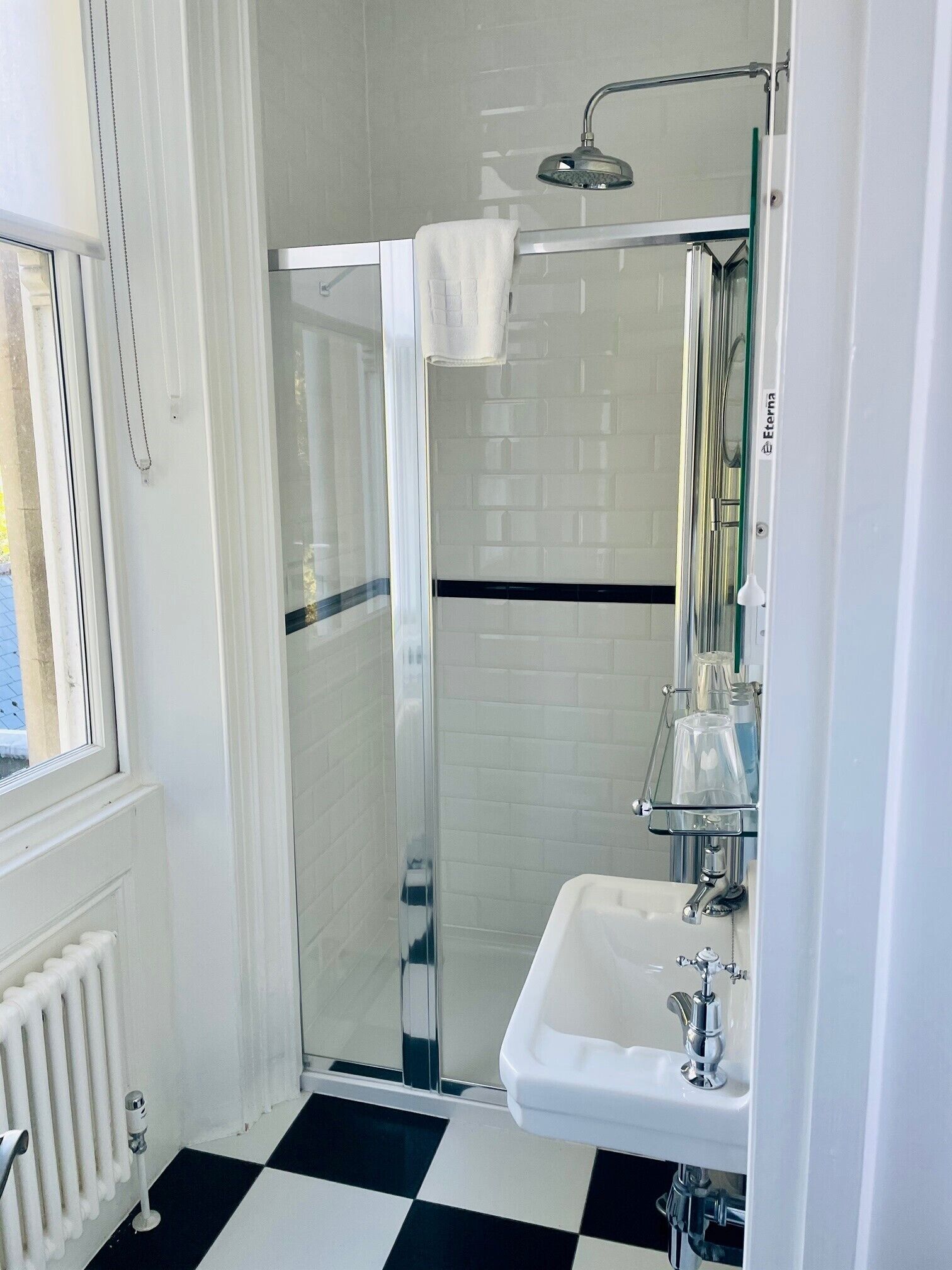 A modern bathroom with a glass-enclosed shower, a white sink, and a tiled floor.
