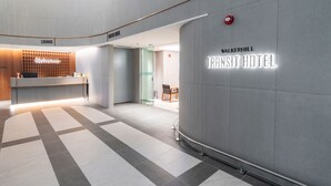 Un hall d’hôtel moderne comprenant un comptoir d’accueil, un espace détente et une enseigne bien visible indiquant « Walkerhill Transit Hotel ».
