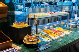 A buffet with various food items, including a cake with macarons and a display of fruits and cheeses.