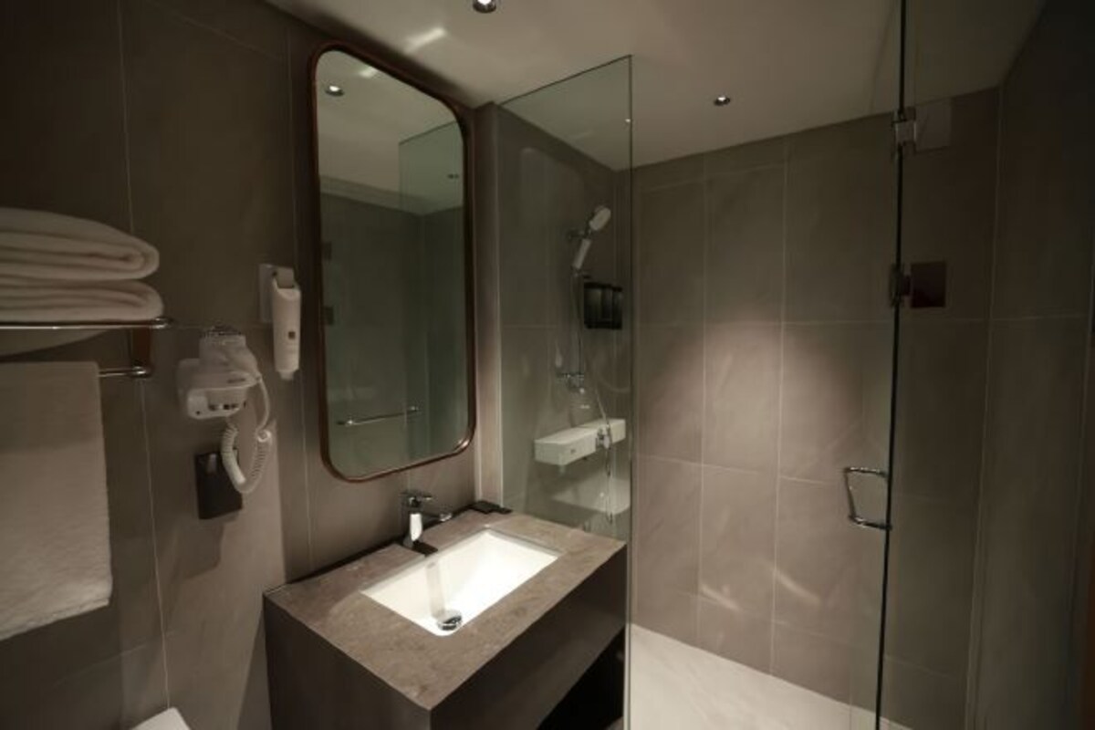 A modern bathroom with a glass shower enclosure, a vanity with a sink, and a mirror.