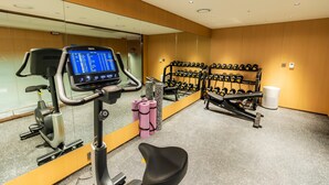 Une salle de sport équipée de matériel d’exercice, d’un miroir et d’un porte-haltères fixé au mur.
