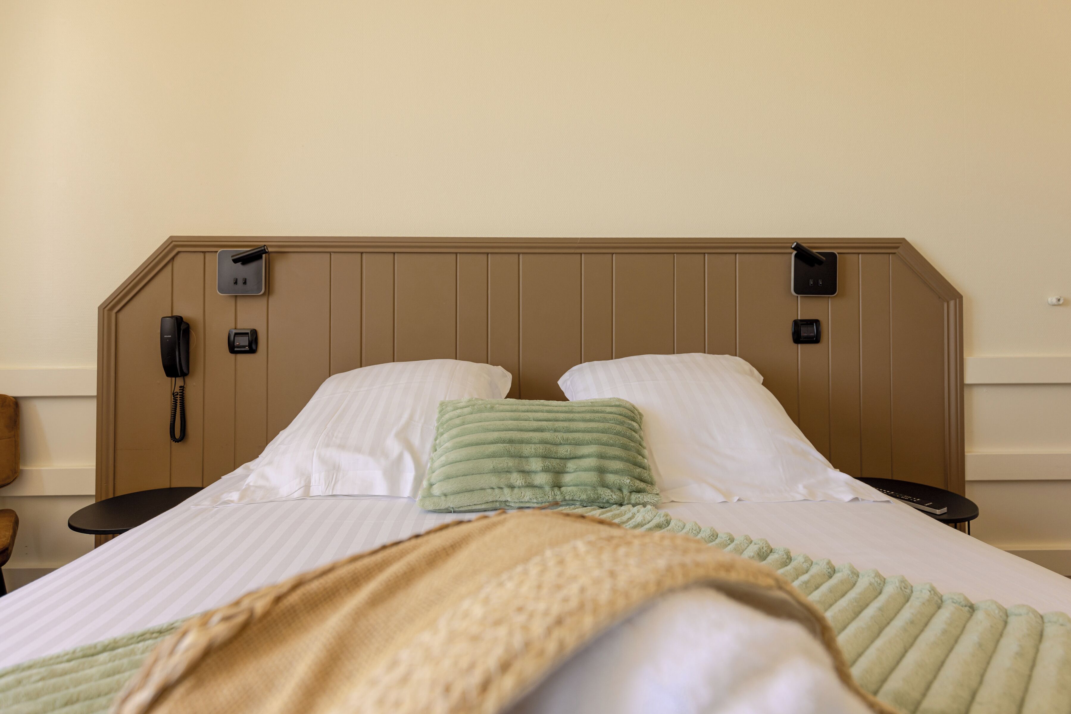 Ein Hotelzimmer mit einem Bett, einem Telefon und einem kleinen Tisch.