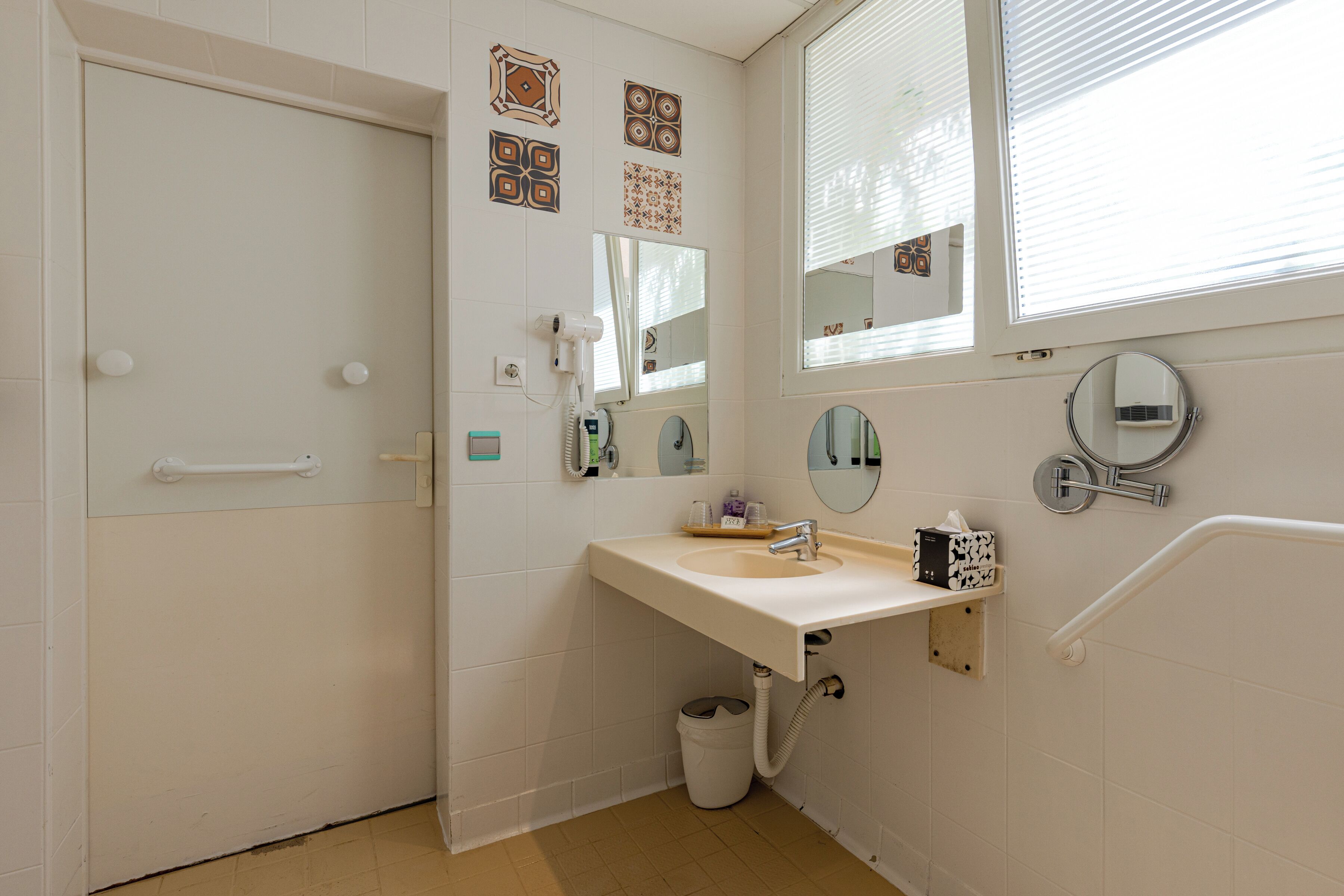 A bathroom with a white sink, mirror, and towel rack.