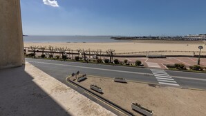 Vista a platja amb cel blau, carretera amb passos de vianants i zona de pàrquing.
