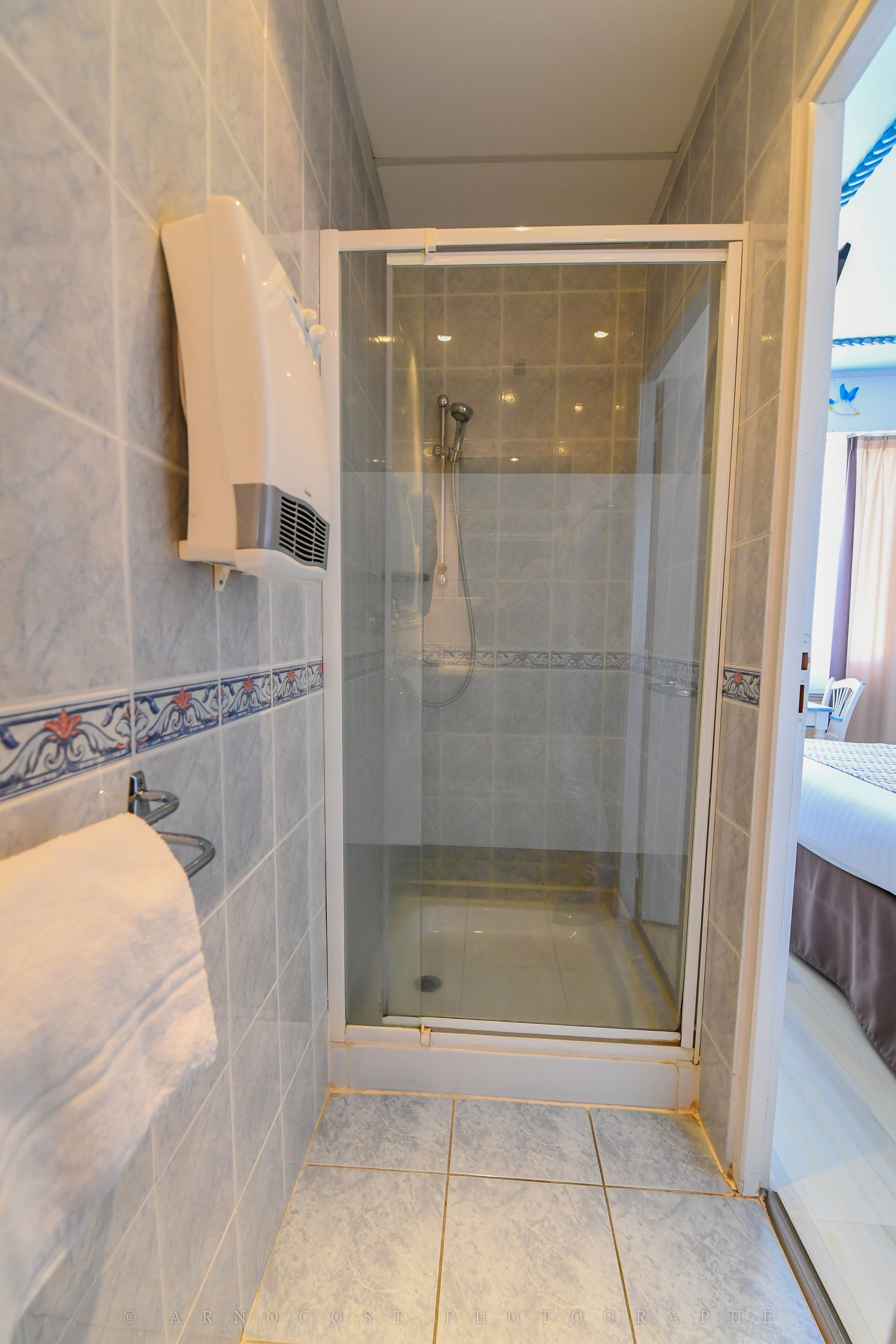 A modern bathroom with a glass-enclosed shower, tiled walls, and a towel rack.