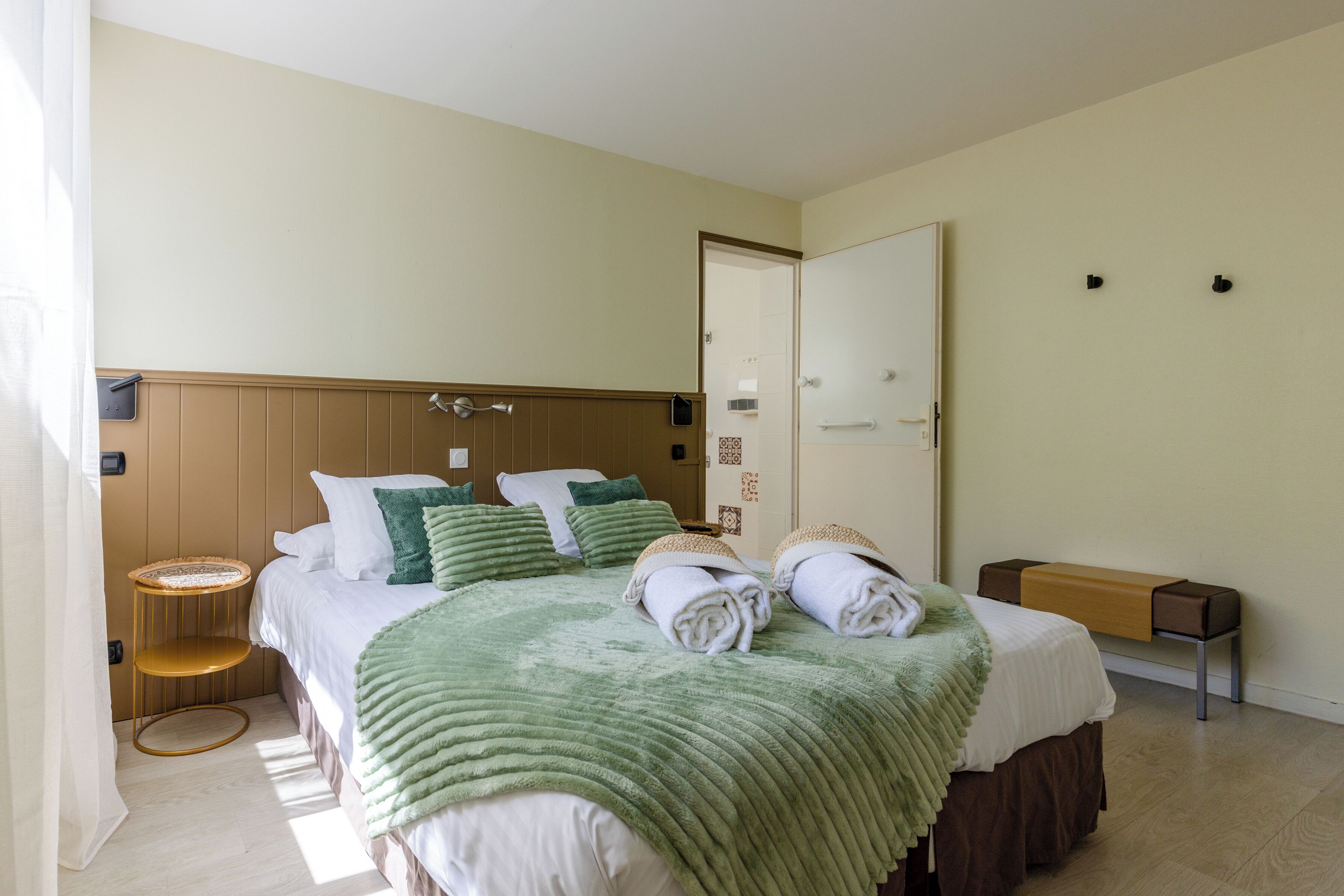 A hotel room with a bed, bedside tables, a wardrobe, and a door.