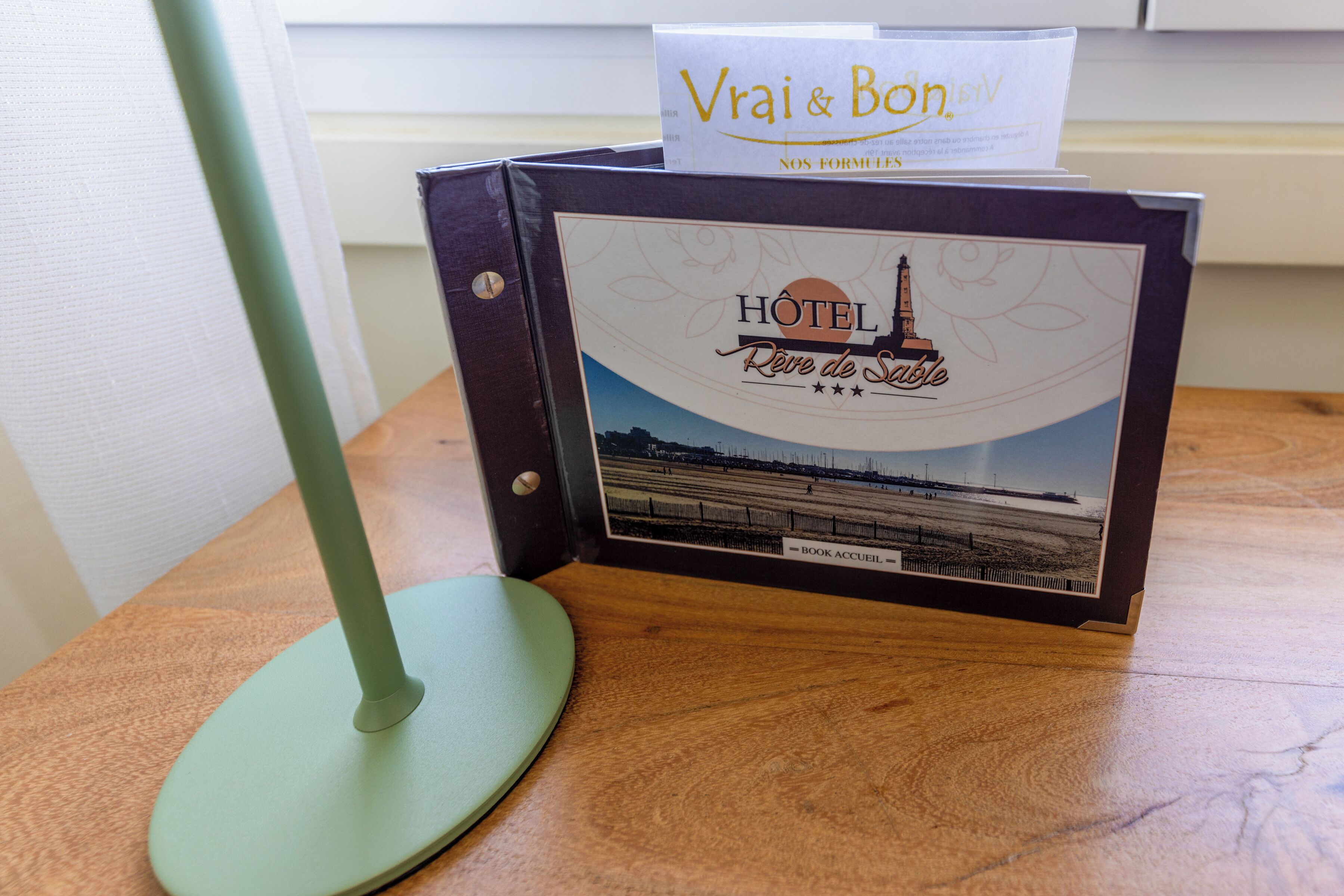 A hotel brochure with a beach scene, a hotel name, and a 'Book Accueil' label.