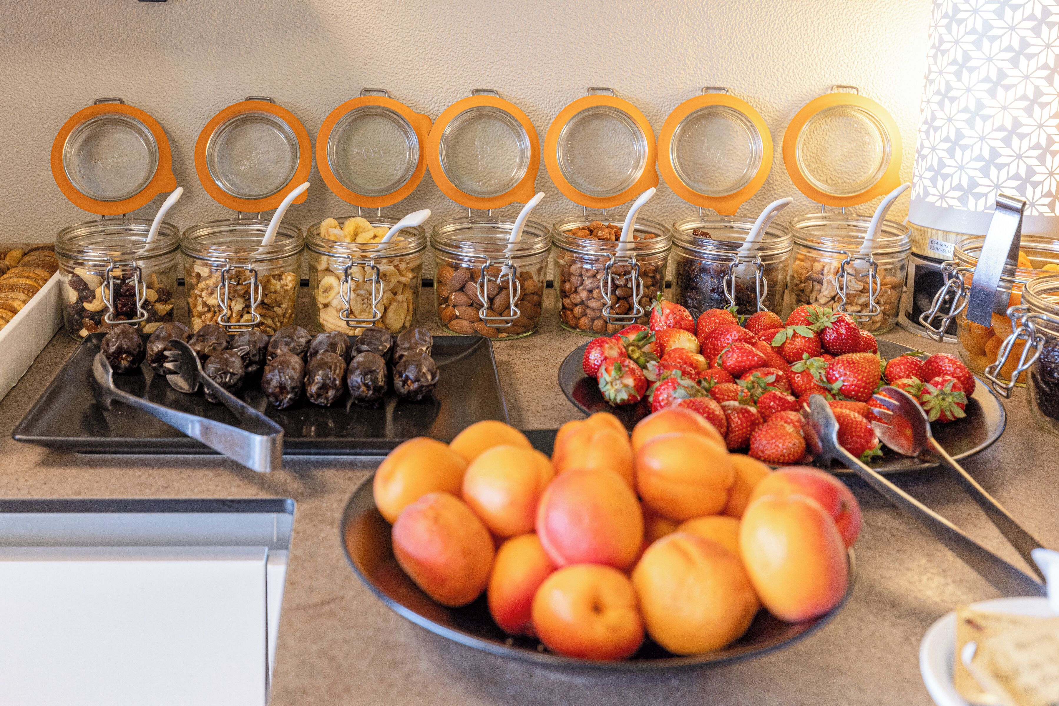 Un bufé con diferentes opciones de comida, incluyendo frutas, nueces y cereales.