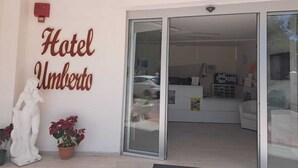 La entrada del Hotel Umberto, con una recepción, una estatua y plantas en macetas.