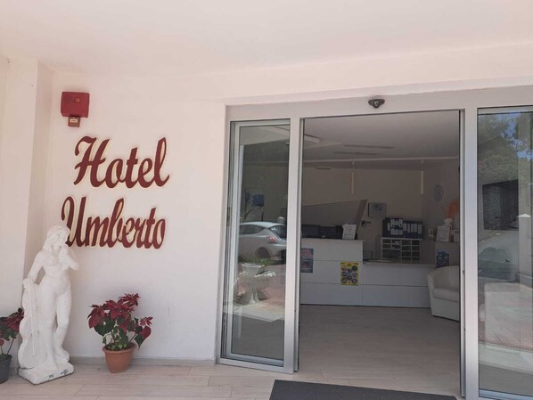 The entrance of Hotel Umberto with a reception desk, a statue, and potted plants. - Hotel Umberto (Ricadi)